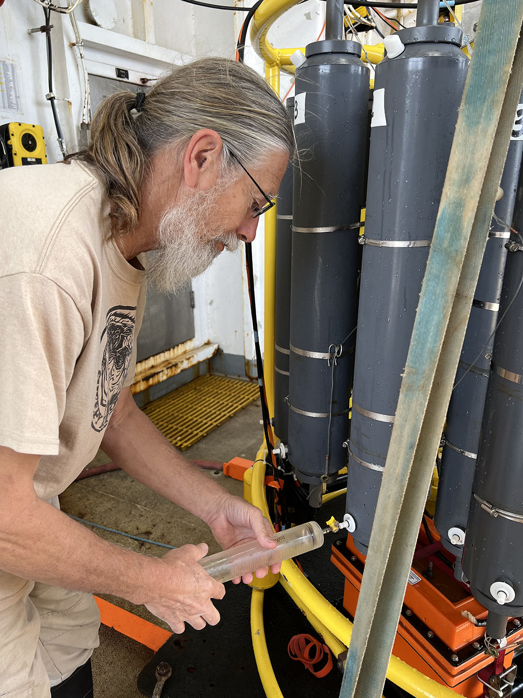 Collecting CFC samples from the CTD rosette is unique, making use of large glass syringes to prevent contamination from the atmosphere, shown here with David Cooper. Photo by Andrew Barna.