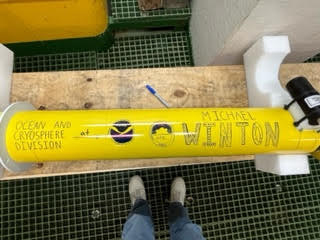 Yellow float lies in a crate with the word "Michael Winton" written on it