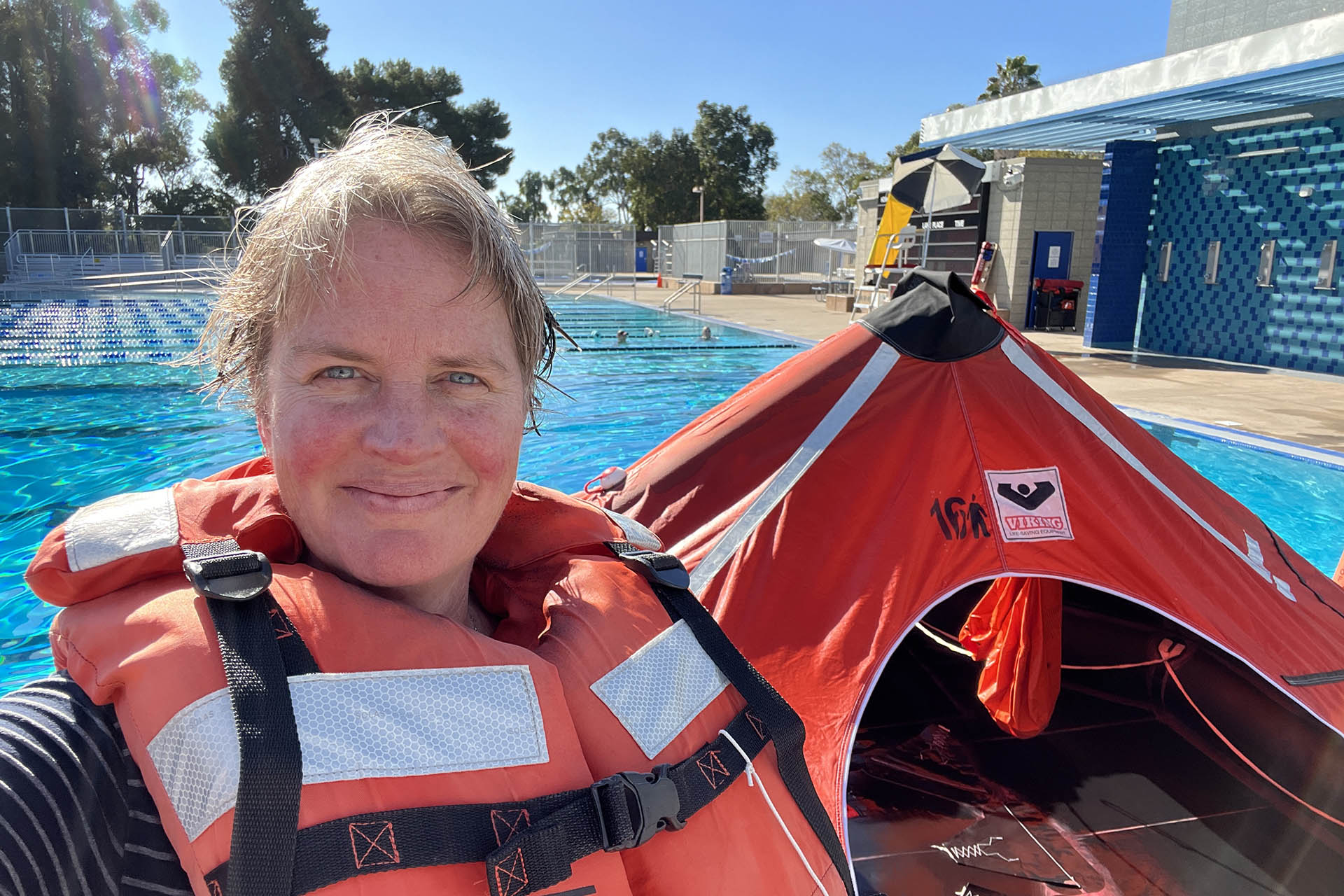 Woman in lifejacket is in front of an inflatable life raft