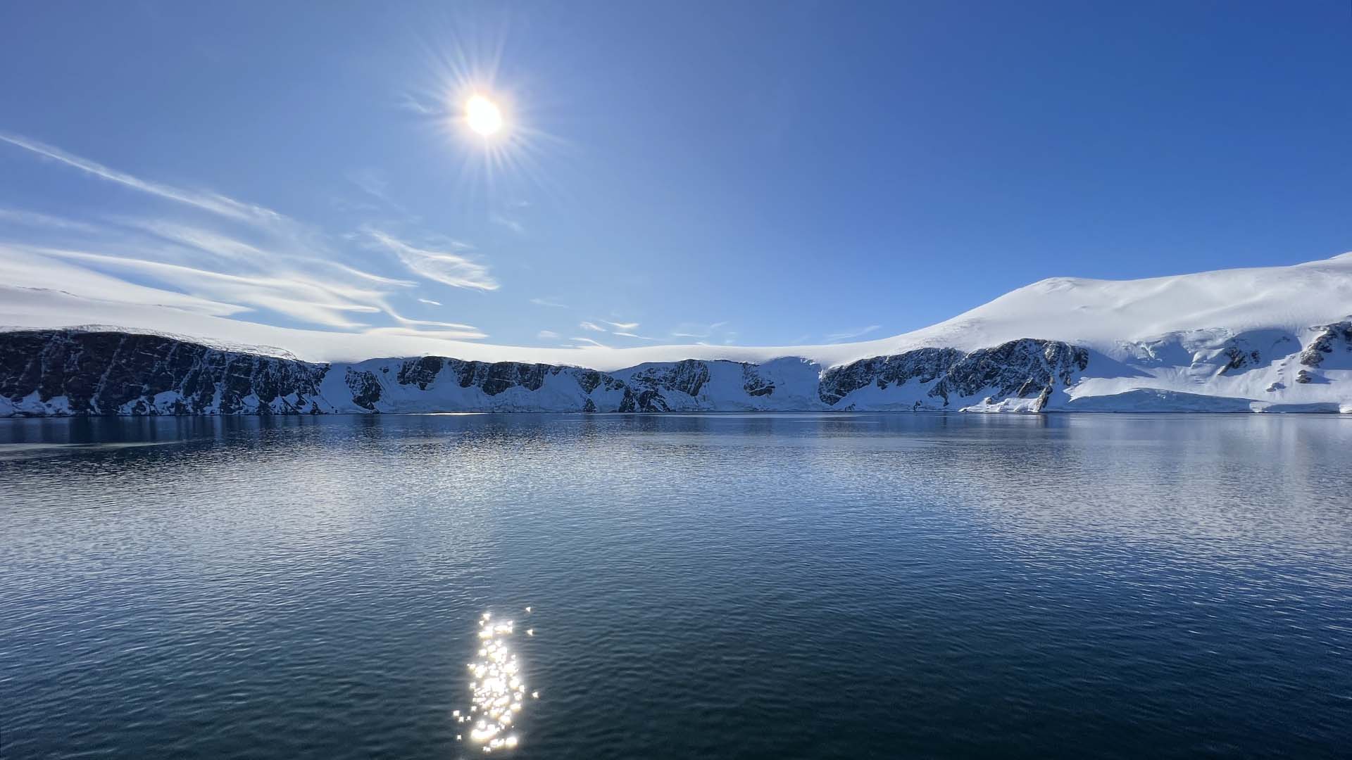 A photo of the bay the next day showing flat seas, blue skies, and a beautiful sun