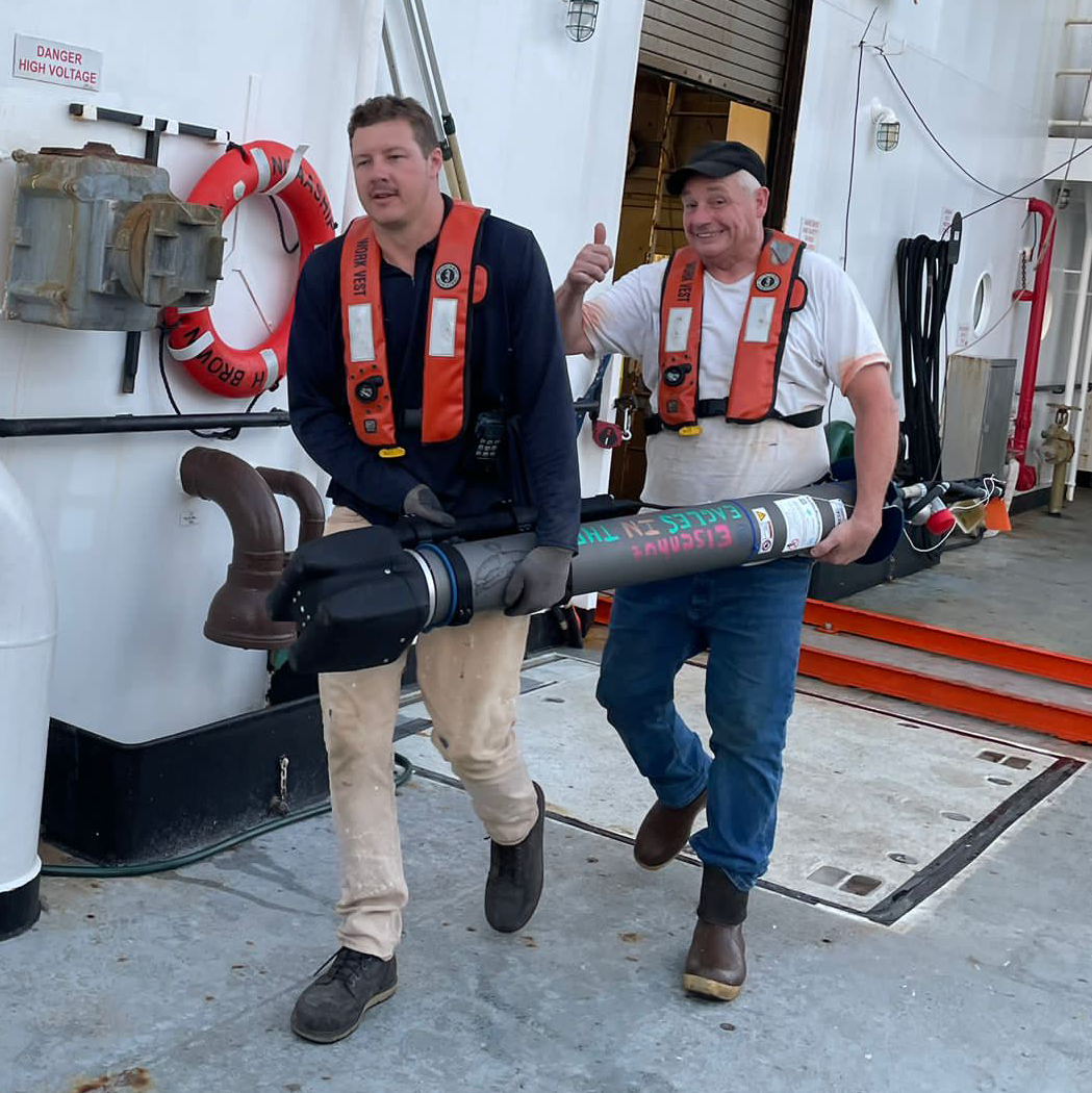 two crew carrying a float - one hand for the ship for safety