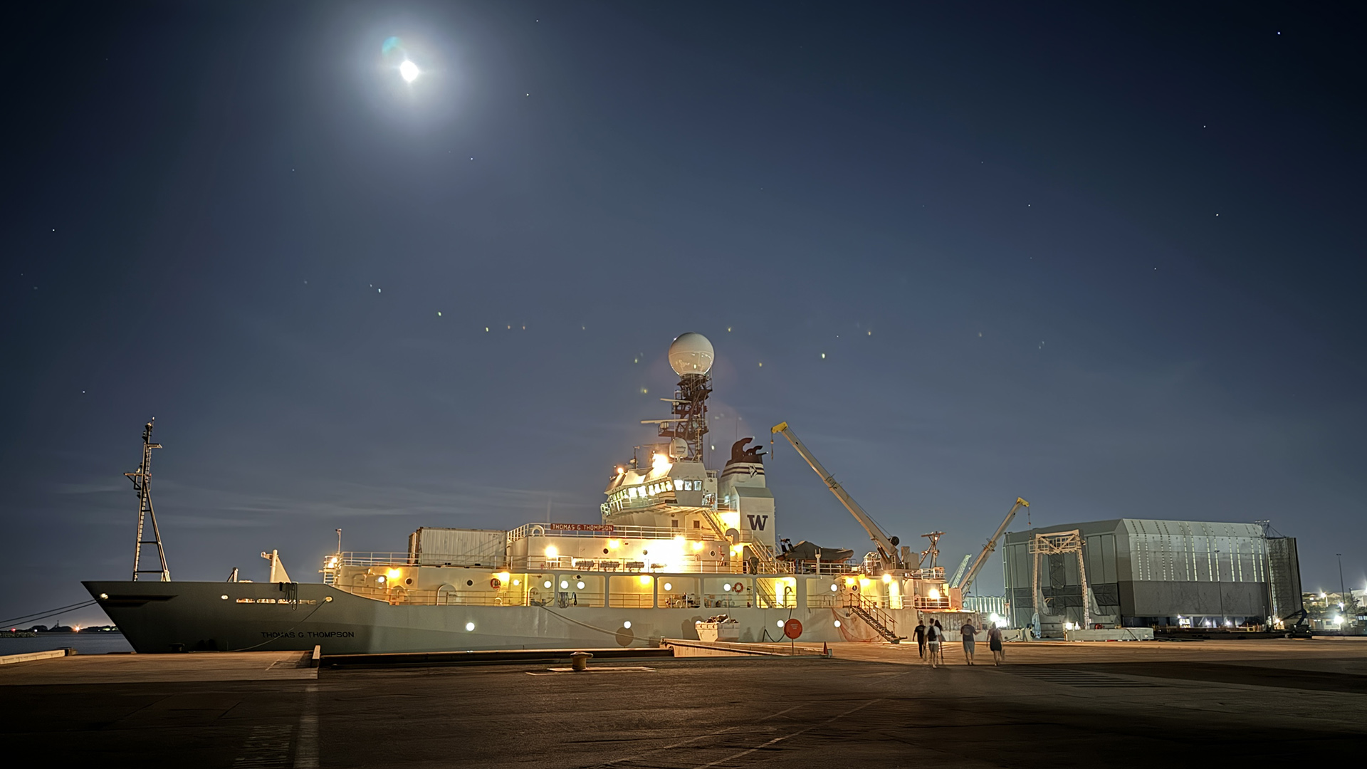 R/V Thomas G Thomson at the dock under a bright moon, as members of the science team board the ship