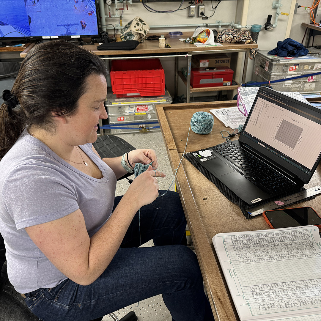 Abby working on a knitting project as her samples process